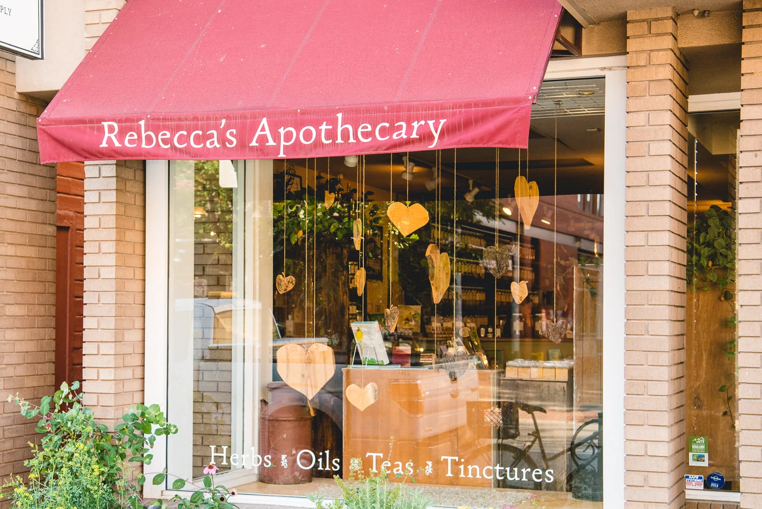 Rebecca’s Apothecary storefront with a red awning and window display.