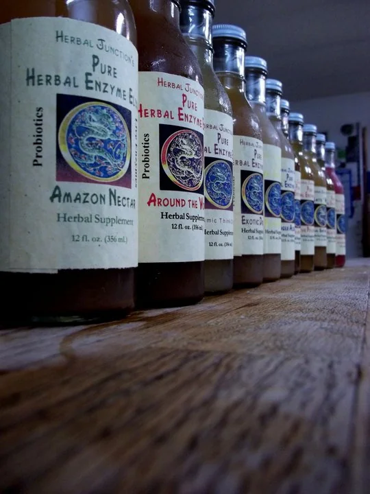 Herbal Junction bottled herbal enzyme elixirs arranged on a wooden counter