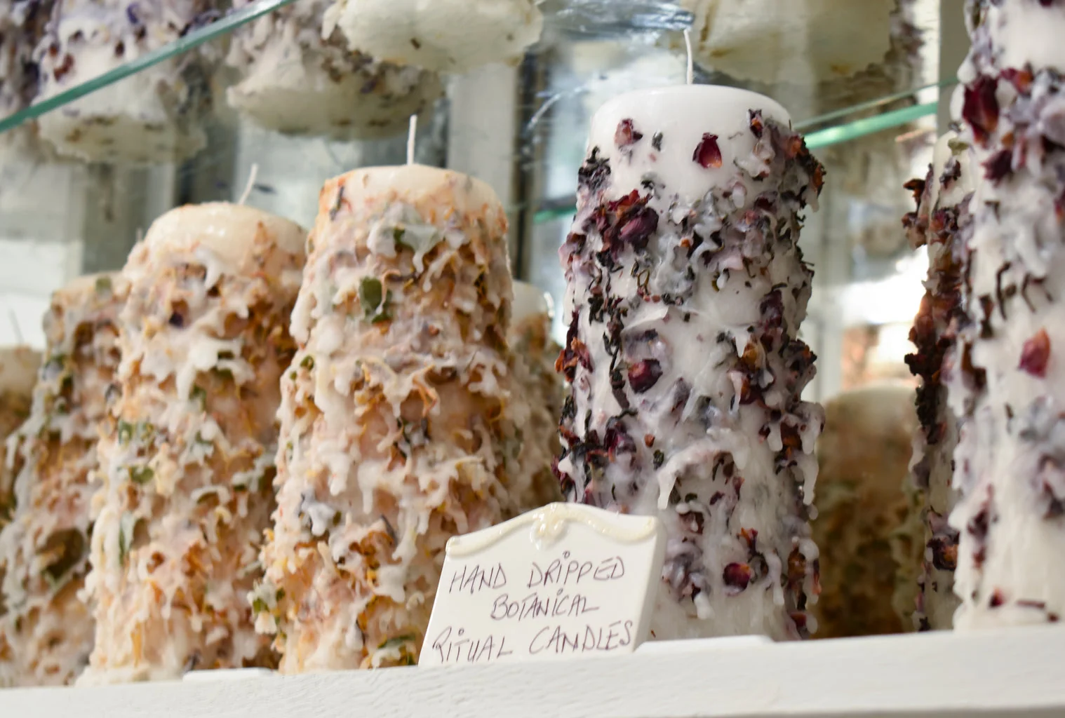 A glass shelf of herbal candles at Raine n River Apothecary